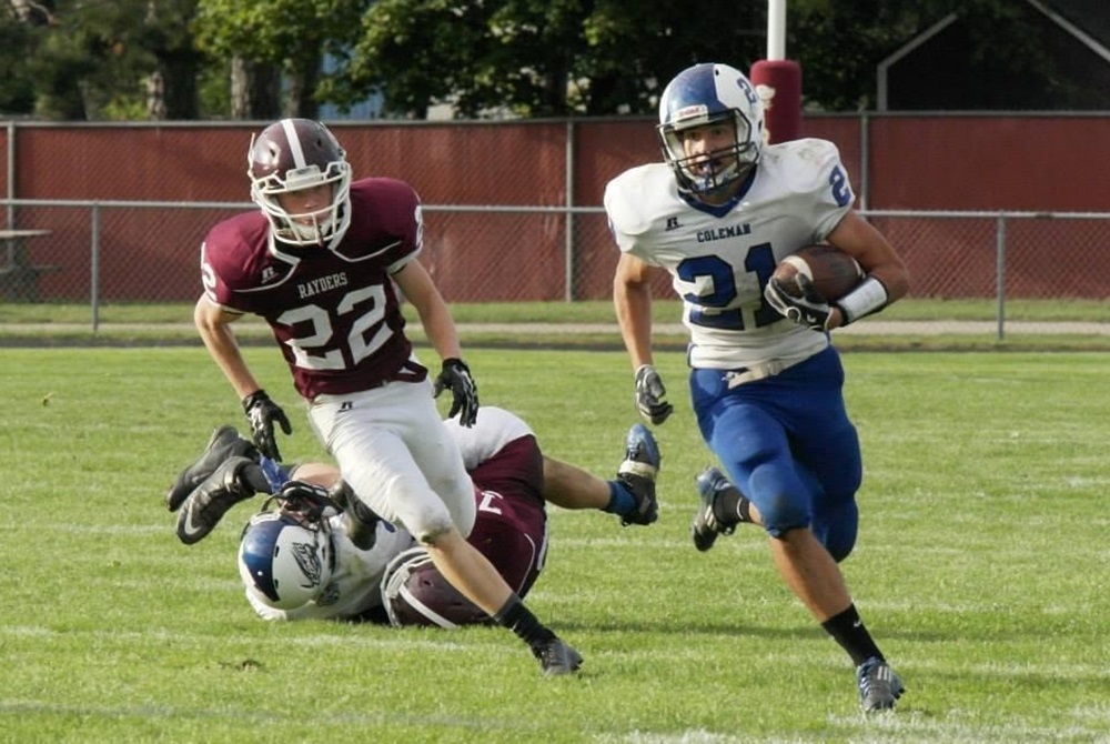 Coleman's Mitch Franklin (right) turns upfield during a 99-yard scoring run against Charlevoix on Sept. 13, 2014.