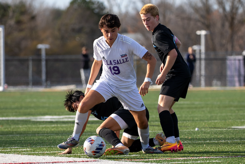 De La Salle’s Vince Houlihan (19) controls the ball while two Forest Hills Northern players attempt to gain possession.