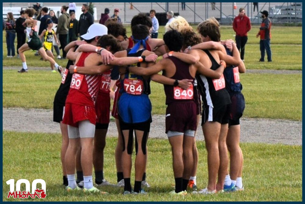 A group of Southwestern Athletic Conference runners huddle up before their races at the 2022 Lower Peninsula Boys Cross Country Finals at Michigan International Speedway, including Bloomingdale’s Jaden Barnes and Joe Stocchiero, Bridgman’s Andrew Mabry and John Sanderson, Centreville’s Logan Weis, Coloma’s Boden Genovese, Constantine’s Ethan Glick, Parchment’s William Winter, Schoolcraft’s Dante Pilot and Watervliet’s Daniel Mandujano.