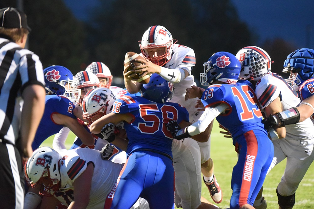 Britton Deerfield’s Caden Kubacki, with the ball, stretches forward for extra yardage against Adrian Lenawee Christian.