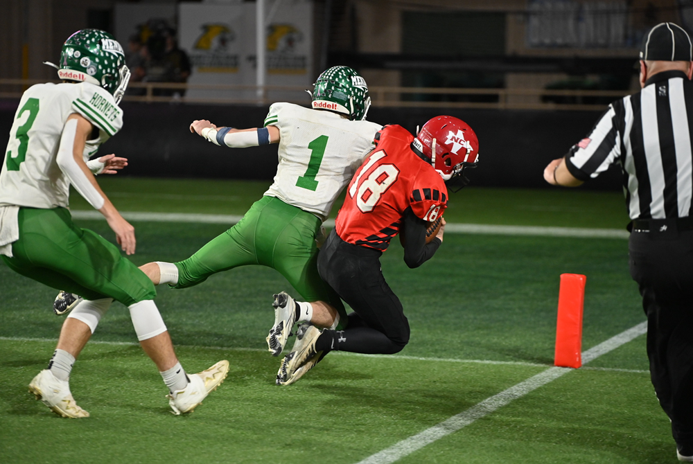 A Powers North Central football player dives for the end zone marker as a Mendon defender attempts to stop him short.