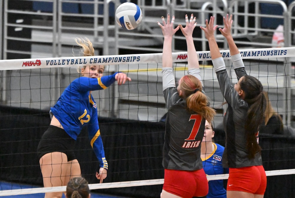 Our Lady of the Lake’s Nora Proos sends a spike into the block of Judge and another teammate Thursday.