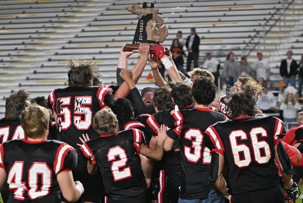 Crystal Falls Forest Park players swarm coach Brian Fabbri (holding trophy) in celebration Saturday at the Superior Dome.