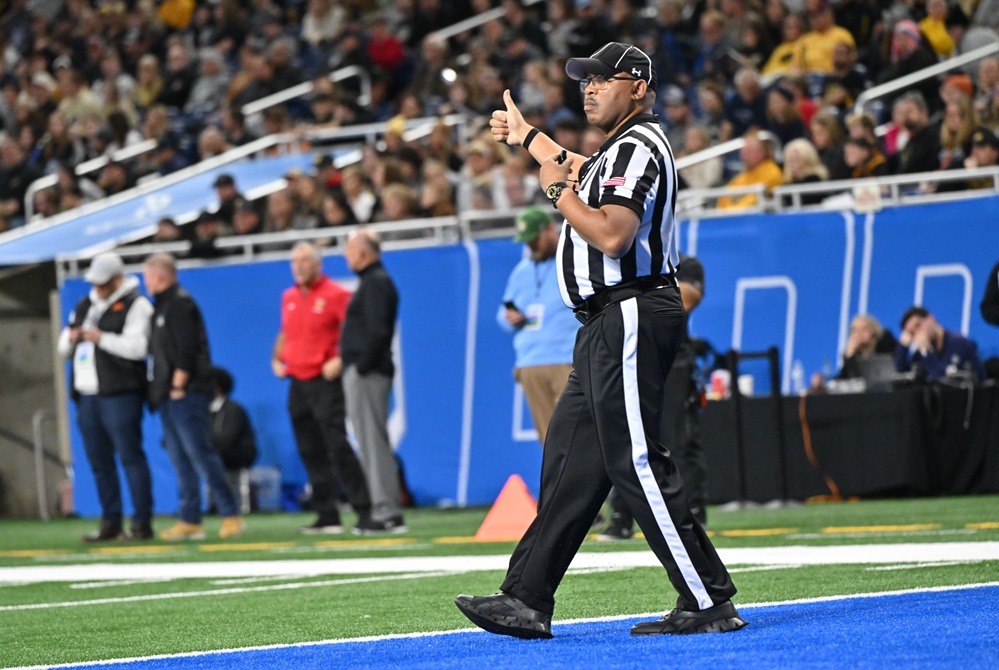 A football official gestures a thumbs up from the end zone during a 2023 championship game. 