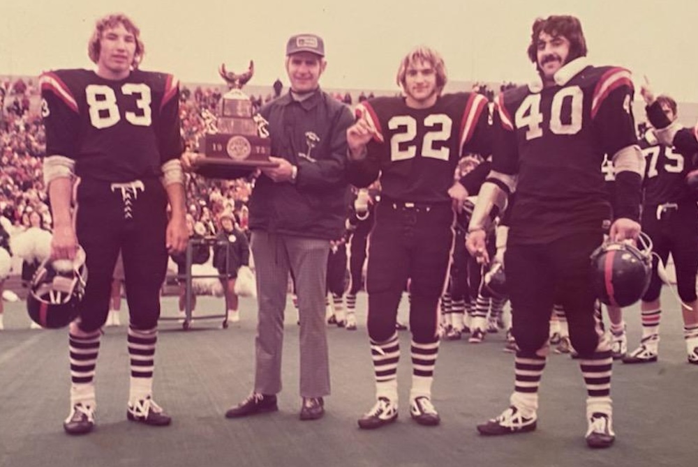 From left: Forest Park’s Bryan LaChapelle, coach Dick Mettlach, Dick Mettlach Jr., and Bill Santilli pose with the first Class D championship trophy Nov. 22, 1975, at Waldo Field in Kalamazoo.