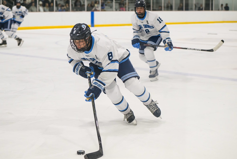 Mona Shores’ Nathan Tilden (8) makes his way up the ice with the puck as twin brother Brady Tilden (18) trails the play.