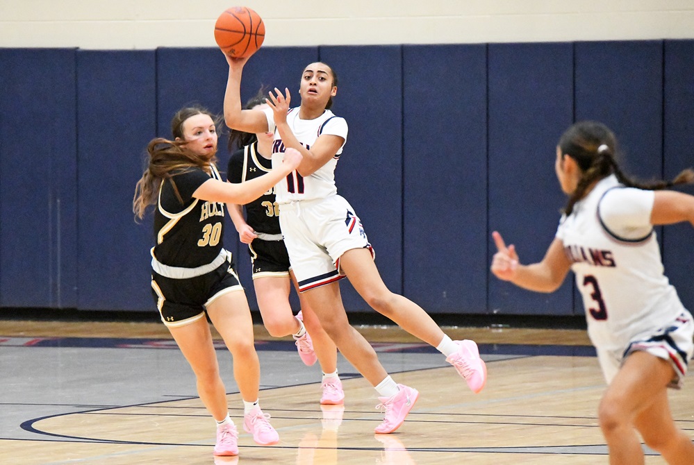 East Lansing’s Sydney Black (11) winds up to send a pass to teammate Navaeh Vasquez while Holt’s Breanna Cornelius attempts to deflect it during the Rams 65-52 win Friday. 