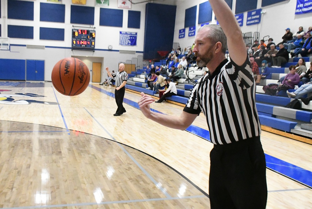 An official requests the basketball on the baseline during a pause in play.