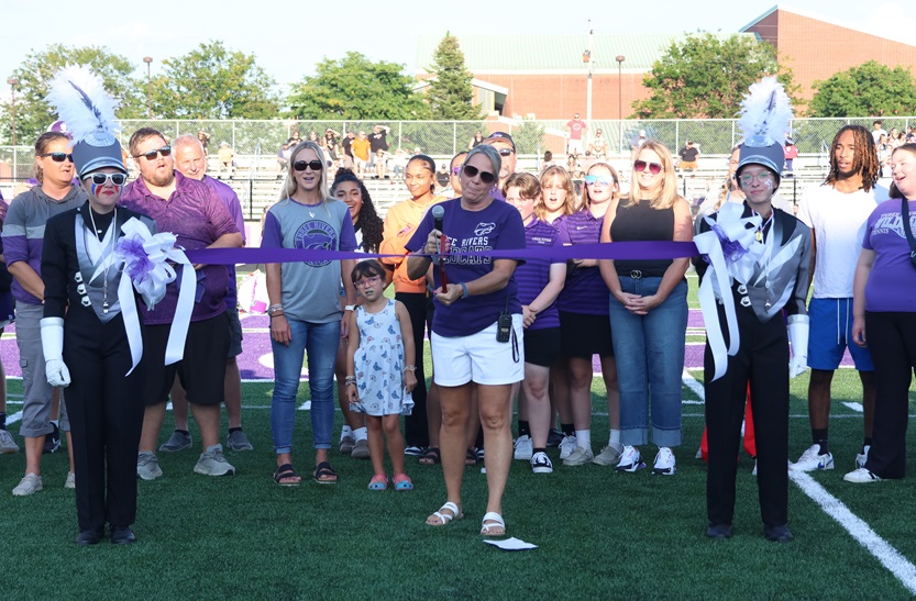 Three Rivers Community Schools superintendent Niki Nash gathers with students, school officials and community members near midfield Aug. 29 to cut the ribbon prior to the first home football game played on newly-renovated Armstrong Field. 