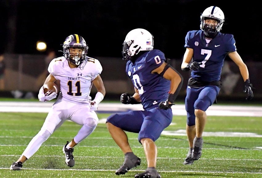 DeWitt’s Jadon Bender (11) cuts back between East Lansing defenders.