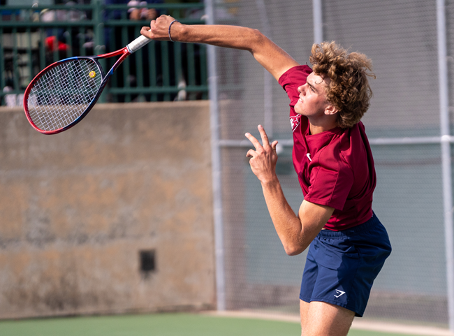 The Maroons’ Tyler Hemmeke serves at No. 2 doubles.