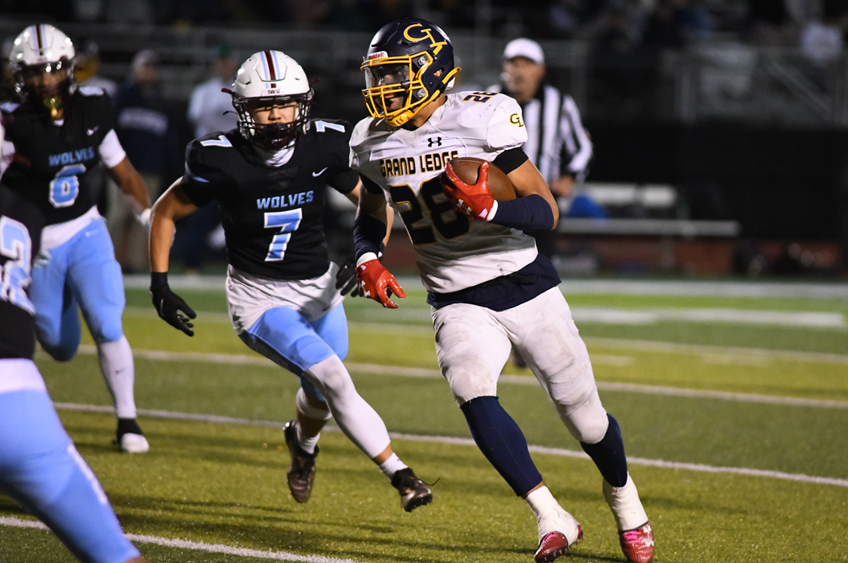 Grand Ledge's Anthony Baker (28) eludes Okemos defenders as Sean Cho (7) pursues during the Comets' 46-10 win.