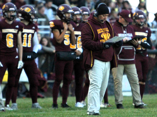 Eagles coach Bill Brown, in headset, checks his chart on the sideline.