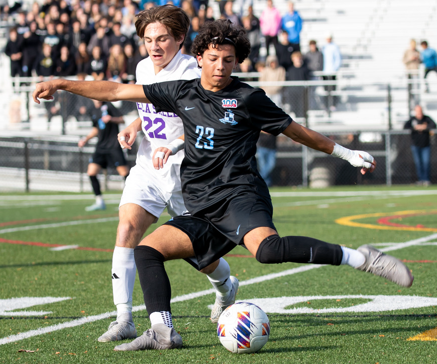 FHN’s Drin Mandija (23) winds up to send the ball forward with the Pilots’ Josh Ross in pursuit. 