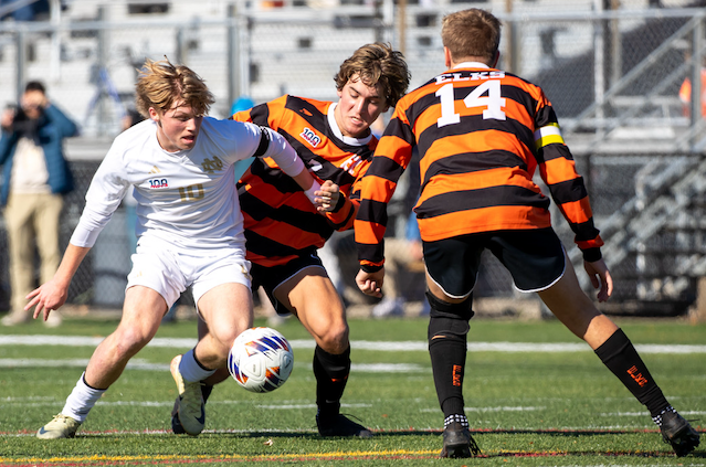 NDP’s Will Lanham (10) works to gain possession against Elk Rapids’ Jonah DenHerder and Jake Garrow (14). 