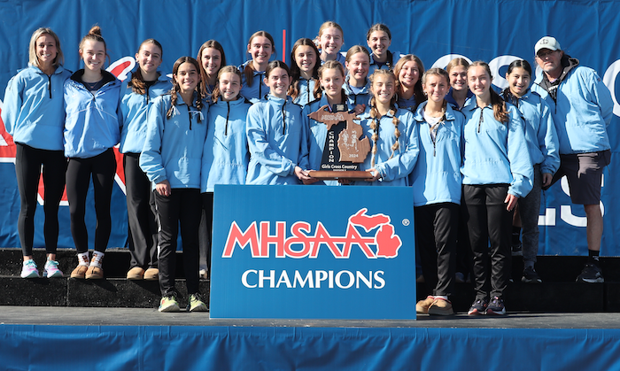 Lansing Catholic holds up its team title trophy. 