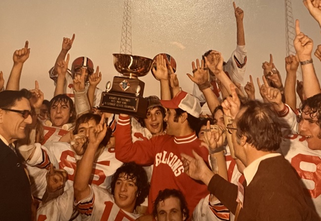 Divine Child players and coaches raise their Prep Bowl trophy in celebration.