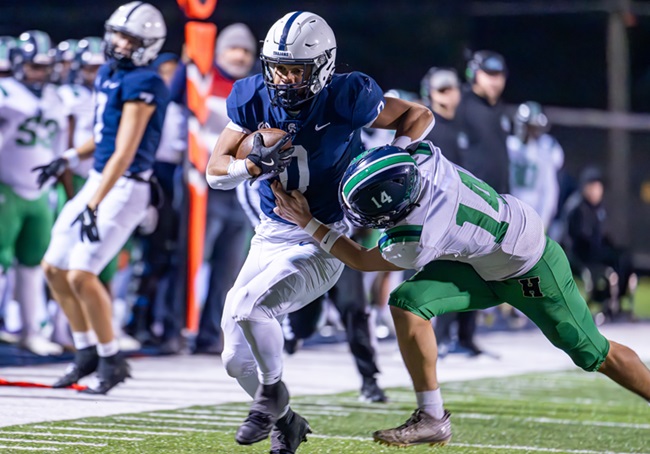 East Lansing’s Jace Clarizio (0) works to break the tackle of Saginaw Heritage’s Anthony Fries.