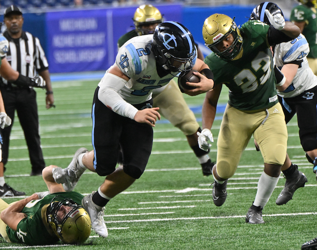 The Cougars’ Alex Fernandez (2) breaks a tackle as Cassius Griffin (23) closes in.