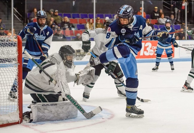 Nathan Tilden raises his leg to allow linemate Eli Habetler's shot past and into the goal against Muskegon Reeths-Puffer last season. Twin brother Brady Tilden looks in on the play.