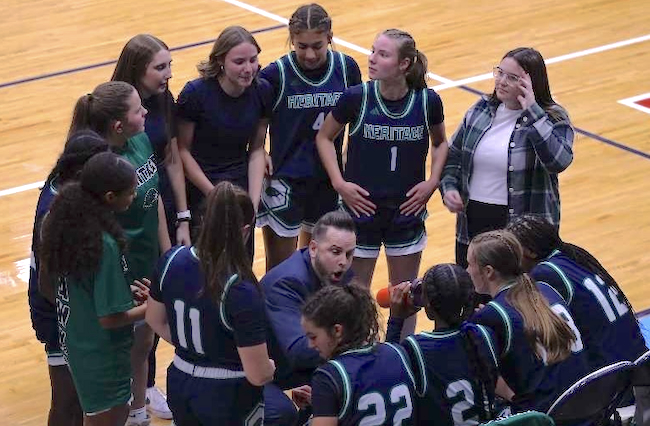 Hawks coach Jaden Clobes (kneeling) huddles with his team.