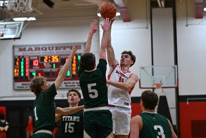 Marquette's Ford Richardson gets up a shot while surrounded by Traverse City West's Ashton Royle (15), Jacob Banish (1), Blake LaFaive (5), and Carter Grubb (3) during the Sentinels’ 69-52 Division 1 District Final win.